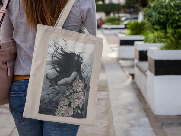 Natural canvas tote bag featuring an artistic black and white illustration with floral details.